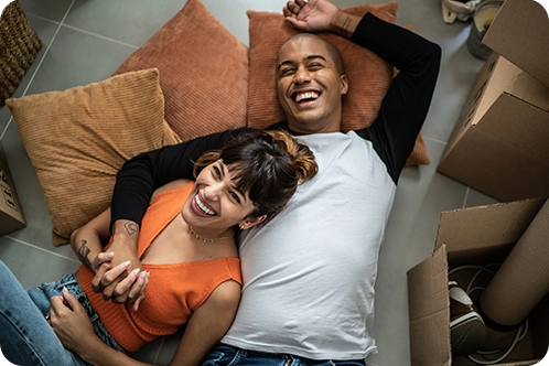 happy couple laughing while laying on floor and taking a break from moving in