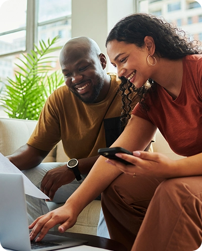 Couple smiling as they look over Midland wealth options on their computer