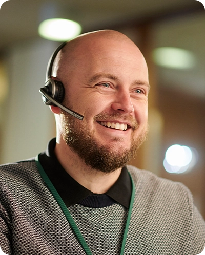 male customer care employee smiling while he talks on headset