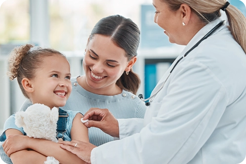 smiling mom holding daughter as doctor talks to her