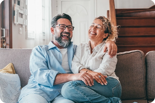 happy couple smiling while on couch at home