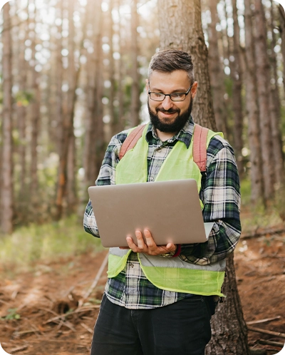 Logger looking at computer while in forest