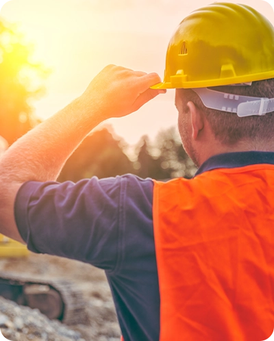 back of male construction worker looking into sunset