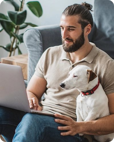 man looking at his computer with his dog next to him