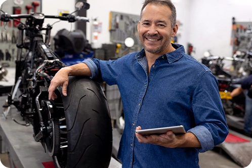 mechanic standing in his shop next to a motorcycle