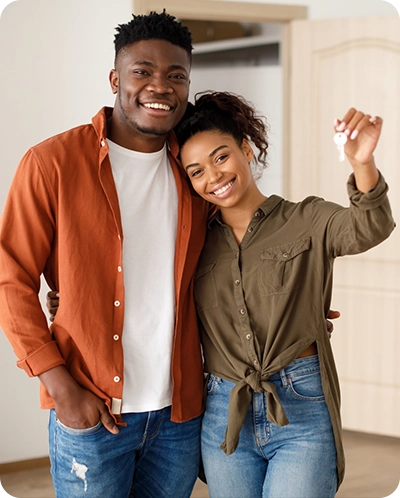 young couple smiling as they hold the keys to their new home