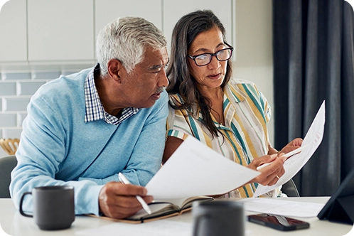 older couple sitting in kitchen looking over papers