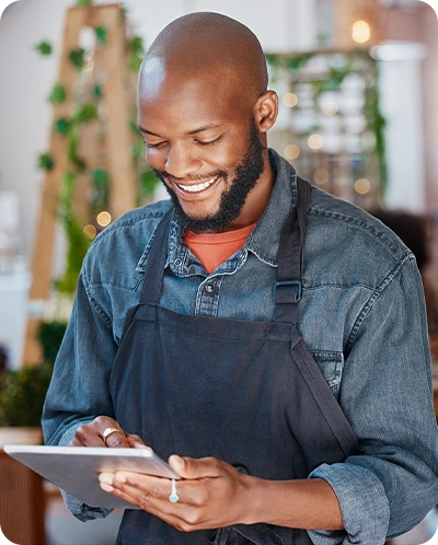 male shop owner smiling while he looks at something on his tablet