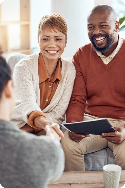 smiling couple shaking hands with a wealth advisor