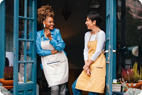 two women small business owners laughing outside their store