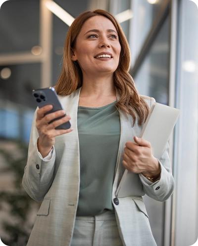 business woman smiling as she walks with her phone