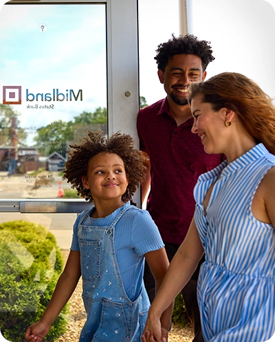 Parents smiling as they walk into Midland bank branch with daughter