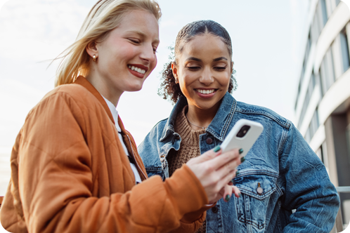 Two women looking at phone while using Zelle